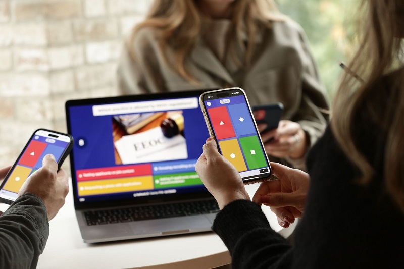 Three professionals participating in a kahoot session on smartphones and a laptop